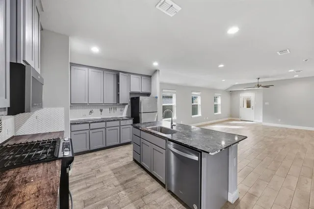 a kitchen with stainless steel appliances granite countertop a sink stove and refrigerator