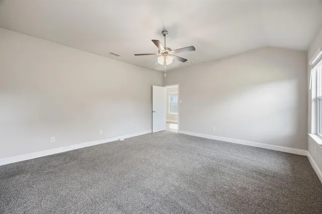 an empty room with a chandelier fan and windows