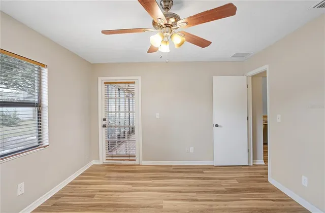 a view of an empty room with window and wooden floor