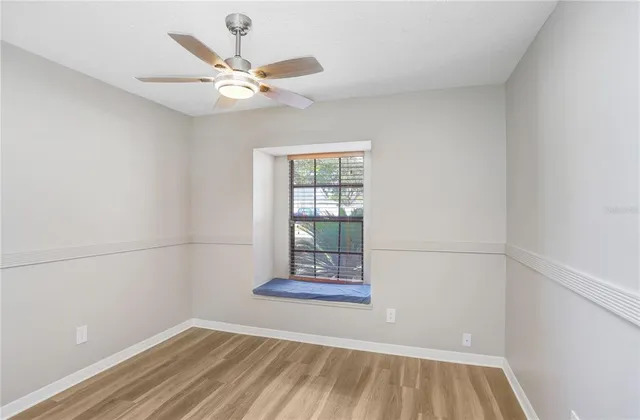 an empty room with a window and a ceiling fan