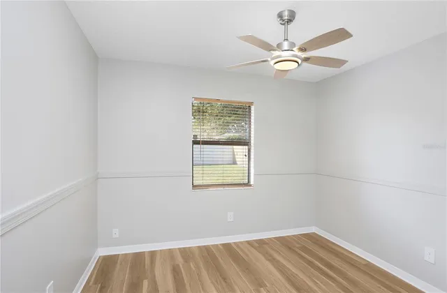 an empty room with a window and a fan