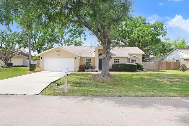 a front view of a house with a garden and tree