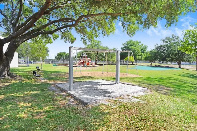 a view of a park with swings and a large tree