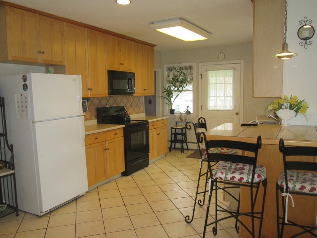 334 Killdeer Road Webster, MA 01570 - Photo 13 of 28 a kitchen with stainless steel appliances a refrigerator a stove a sink a dining table and chairs