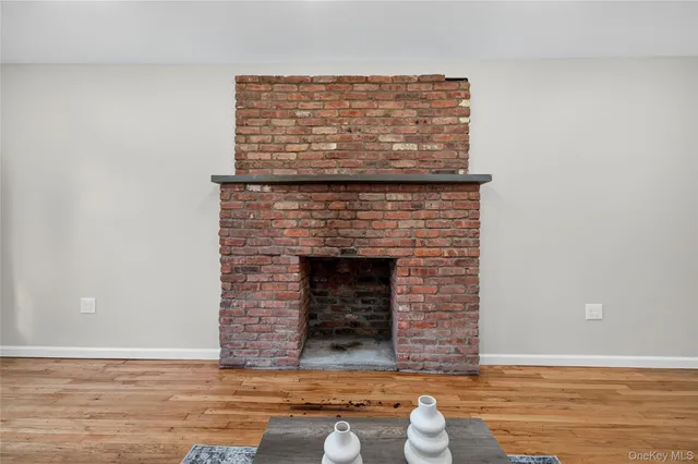 a view of an empty room with wooden floor and a fireplace