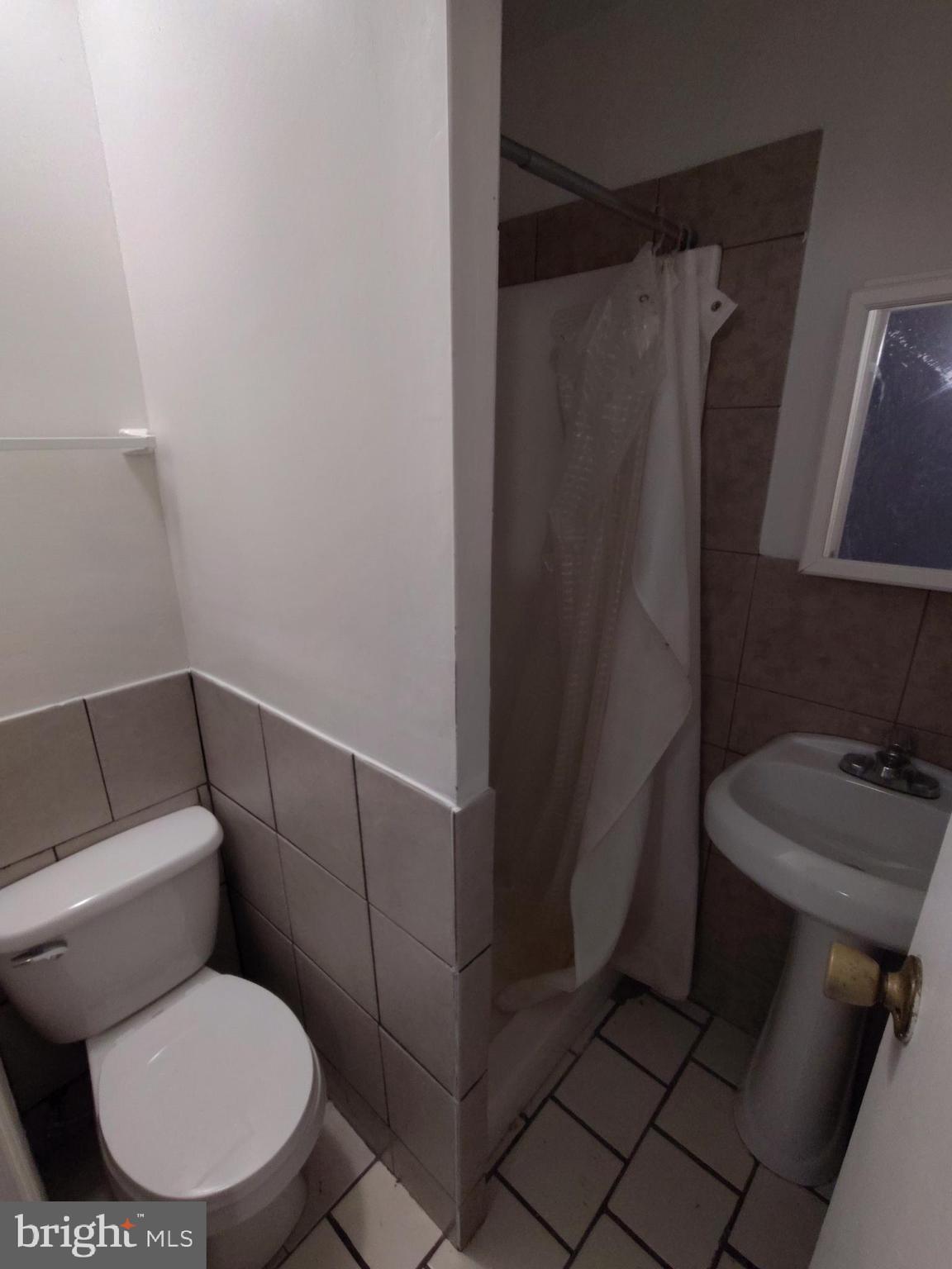 1607 Page Street Philadelphia, PA 19121 - Photo 12 of 14 a white toilet sitting next to a shower curtain