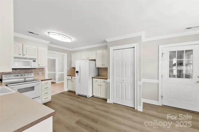 a large kitchen with white cabinets stainless steel appliances a window and a counter top space