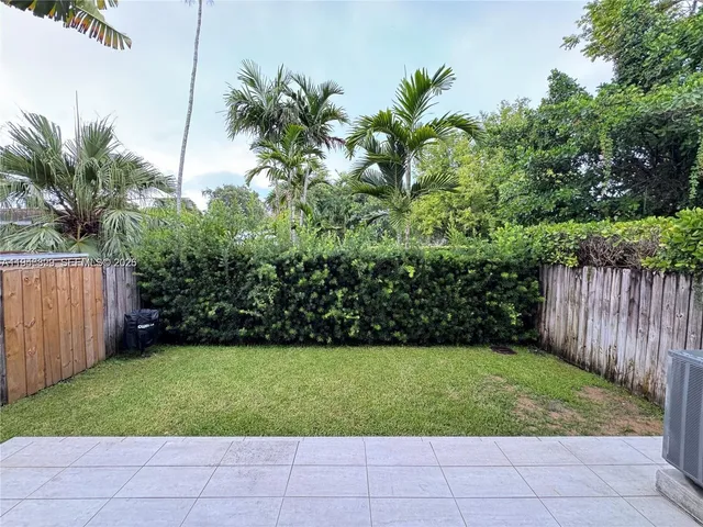 a view of a yard with potted plants and large trees