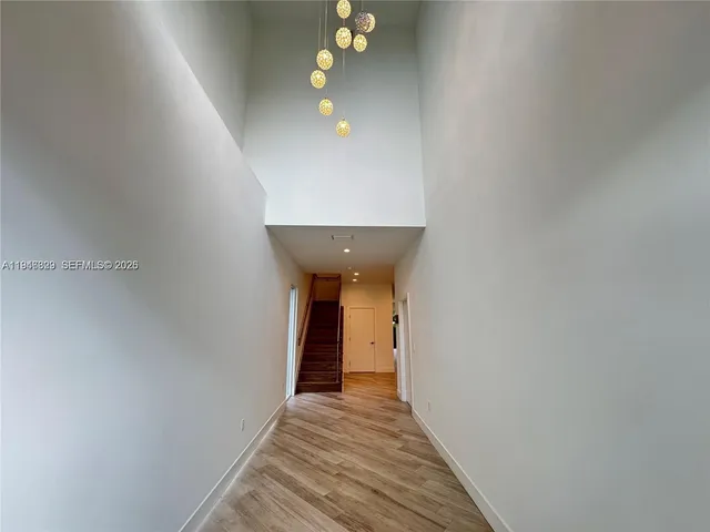 a view of a hallway with wooden floor and a chandelier