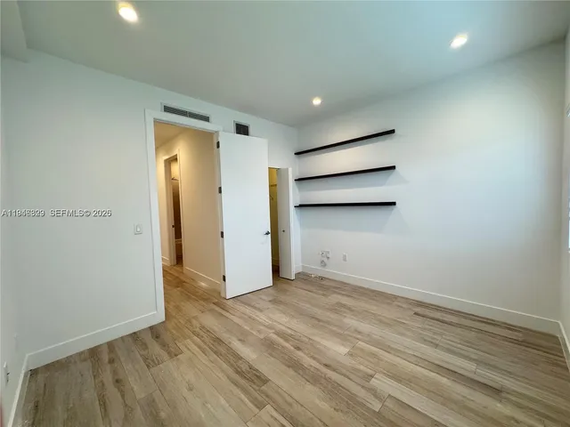 a view of an empty room with wooden floor and closet