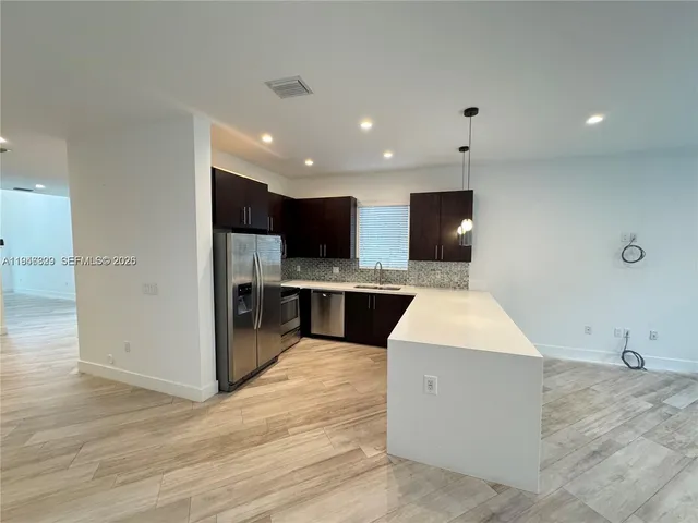 a large kitchen with stainless steel appliances kitchen island a large counter top and a wooden floors