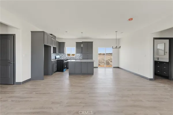 a view of kitchen with kitchen island a sink wooden floor and stainless steel appliances