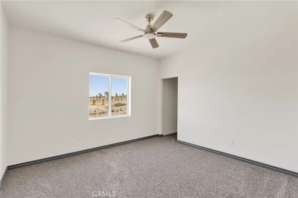 an empty room with a ceiling fan and window