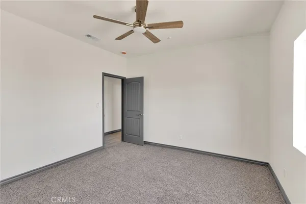 an empty room with a ceiling fan and a window