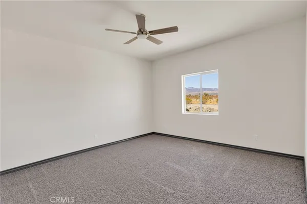 an empty room with a ceiling fan and window