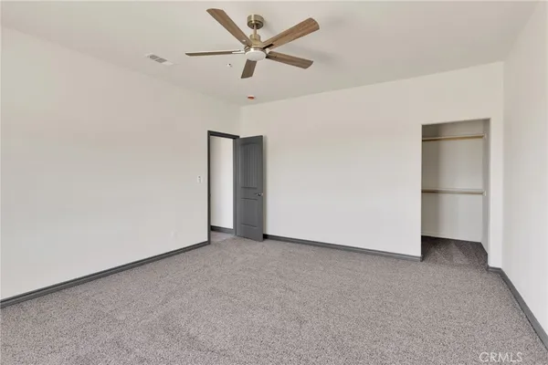 an empty room with closet and a ceiling fan