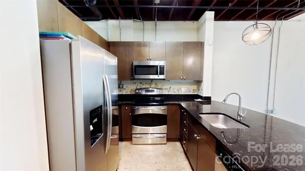 a kitchen with stainless steel appliances granite countertop a sink a stove a refrigerator a washer and dryer