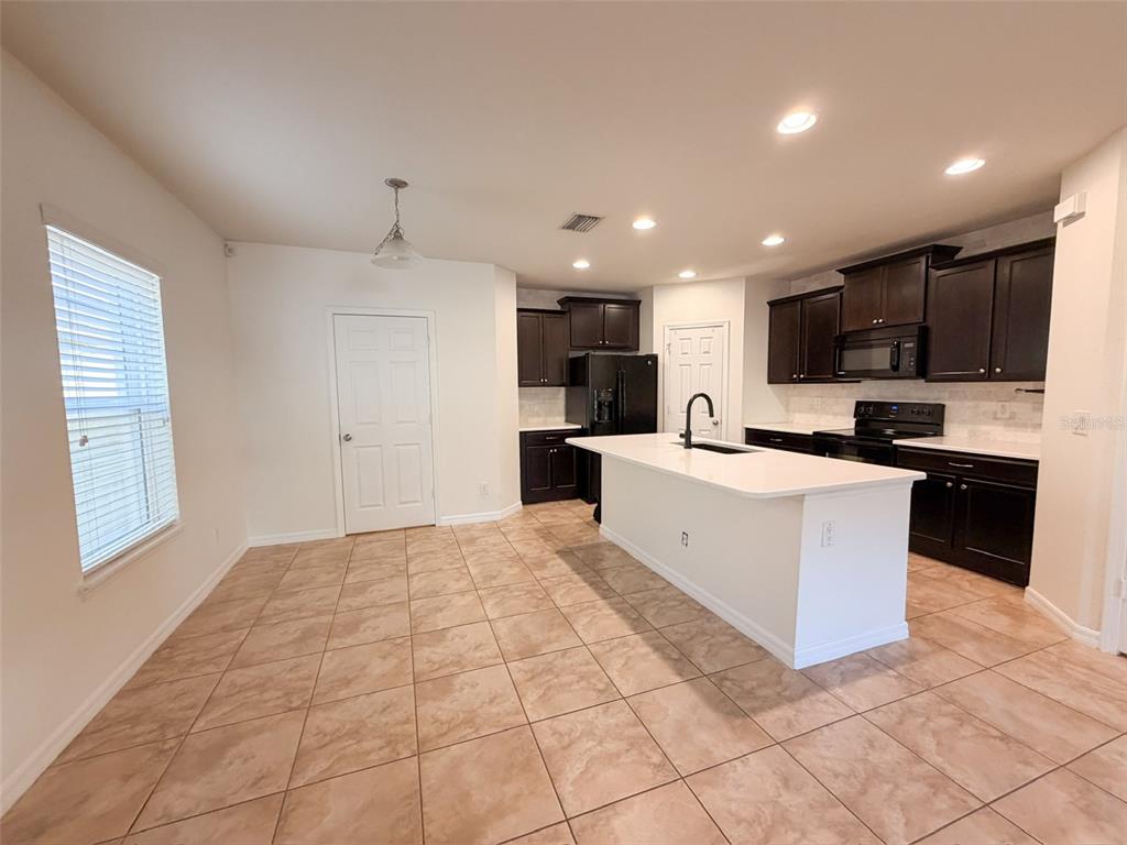 4747 Chatterton Way Riverview, FL 33578 - Photo 5 of 24 a large white kitchen with kitchen island a stove a sink a refrigerator and a counter top space