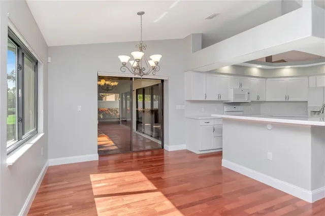 a view of a hallway with wooden floor and chandelier