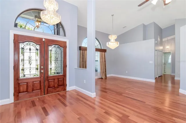 a view of a hallway with wooden floor and a chandelier