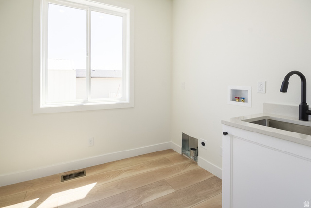 3322 250 S Street Vernal, UT 84078 - Photo 13 of 37 Laundry area featuring wood-finish flooring, a white-framed window, and a utility sink with a matte black faucet set into a light-toned countertop