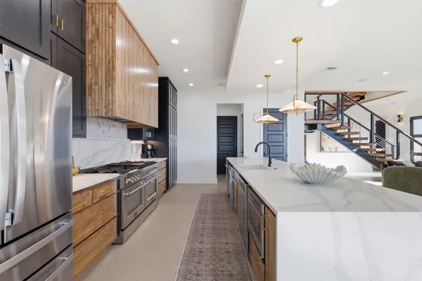 a kitchen with stainless steel appliances kitchen island granite countertop a refrigerator a stove and a sink with wooden floor