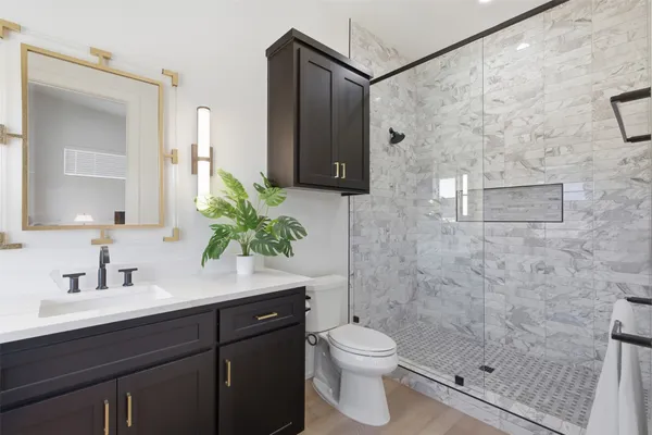 a bathroom with a sink a toilet a shower and a mirror