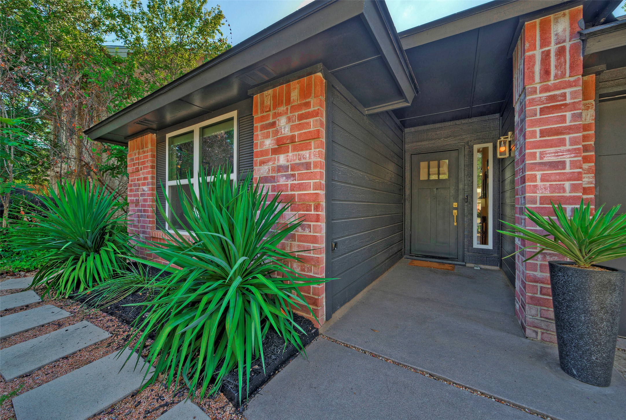 8406 Los Ranchos Drive Austin, TX 78749 - Photo 2 of 32 A welcoming entry features a dark grey door and vibrant landscaping, enhancing its curb appeal.