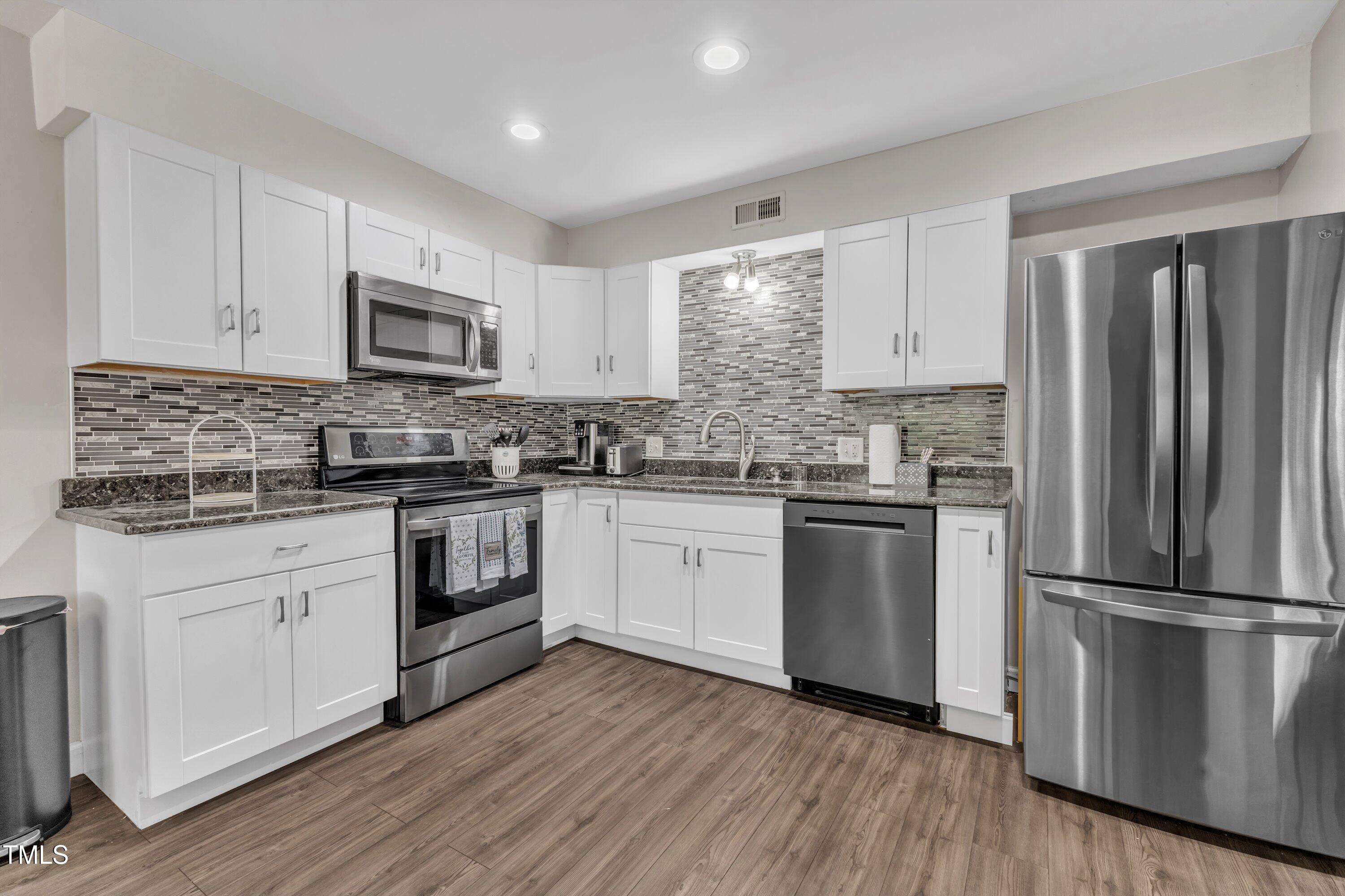 5022 Flint Ridge Place Raleigh, NC 27609 - Photo 7 of 32 a kitchen with a refrigerator stove and white cabinets