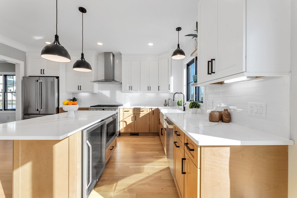 a kitchen with stainless steel appliances granite countertop a sink a stove a refrigerator and island with wooden floor