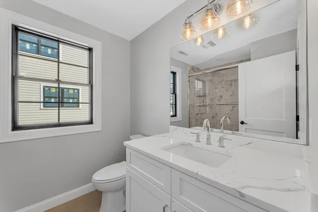 a bathroom with a sink toilet and large mirror