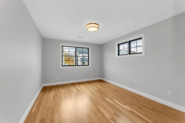 an empty room that has a window and a wooden floor