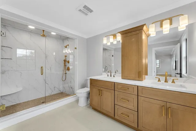 a spacious bathroom with a double vanity sink toilet mirror and bathtub