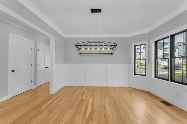 a view of a room with wooden floor chandelier and windows