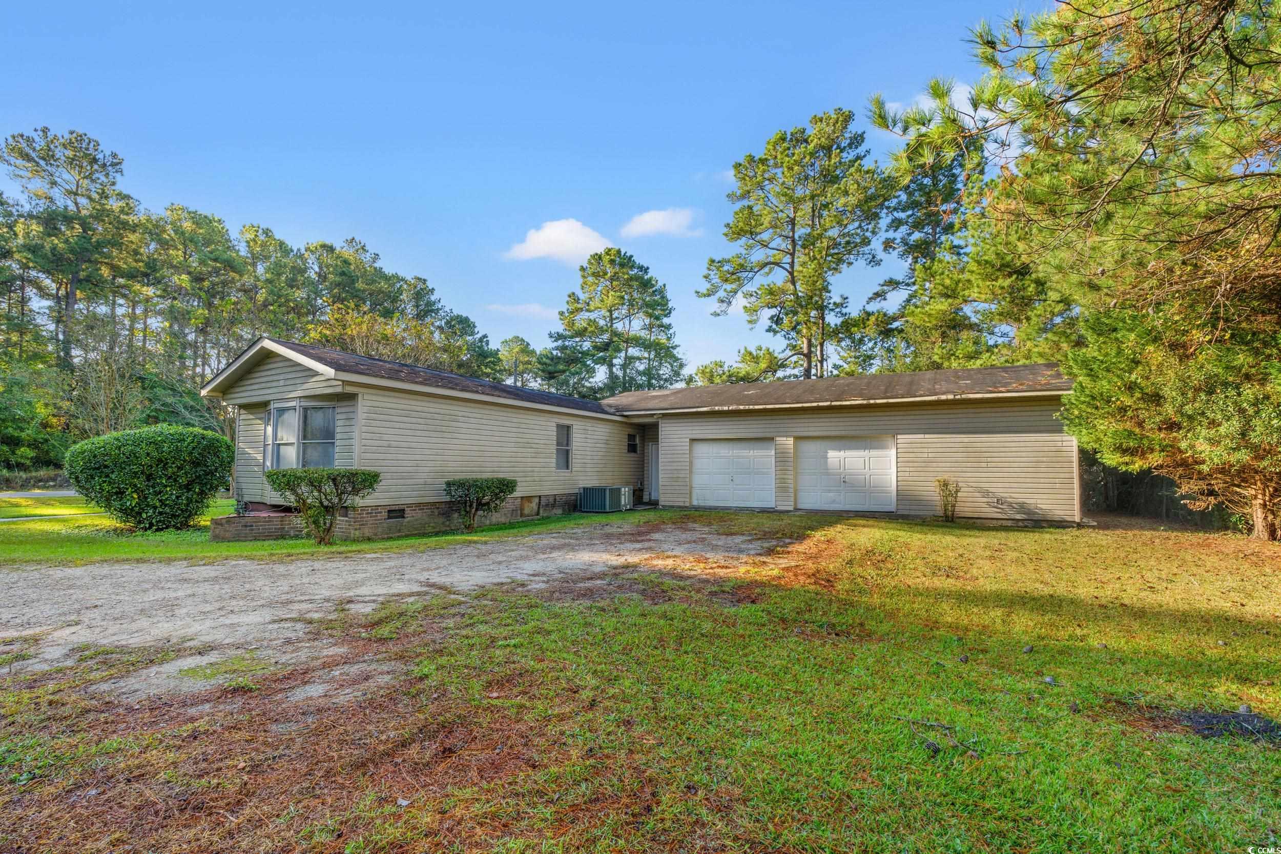 149 William Street Loris, SC 29569 - Photo 33 of 40 View of front of house featuring dirt driveway, a front lawn, and an attached garage