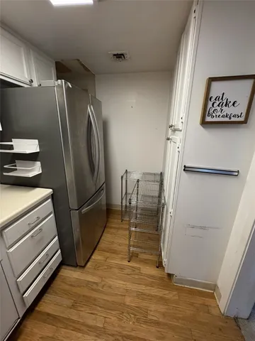 a view of a refrigerator in kitchen and an empty room