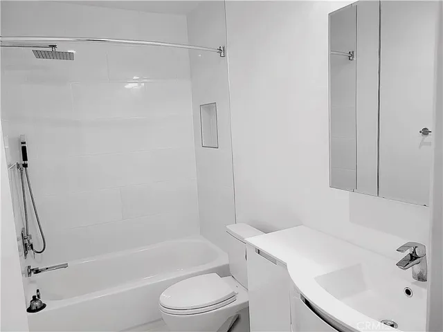 a bathroom with a bathtub shower sink vanity and toilet