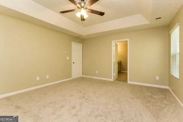 an empty room with a ceiling fan and a window