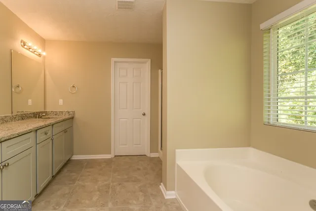 a bathroom with a granite countertop sink and a bathtub