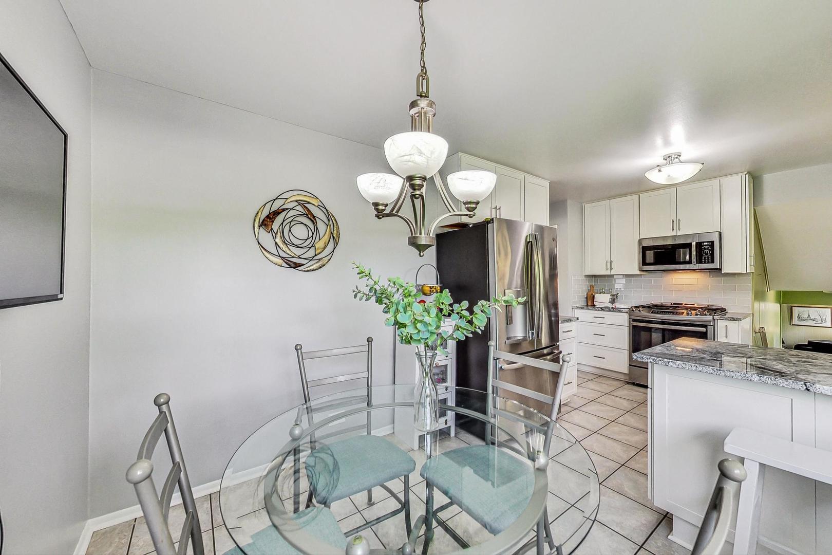 910 Whitegate Drive Mount Prospect, IL 60056 - Photo 16 of 38 a kitchen with stainless steel appliances granite countertop a refrigerator a stove a sink a dining table and chairs with wooden floor