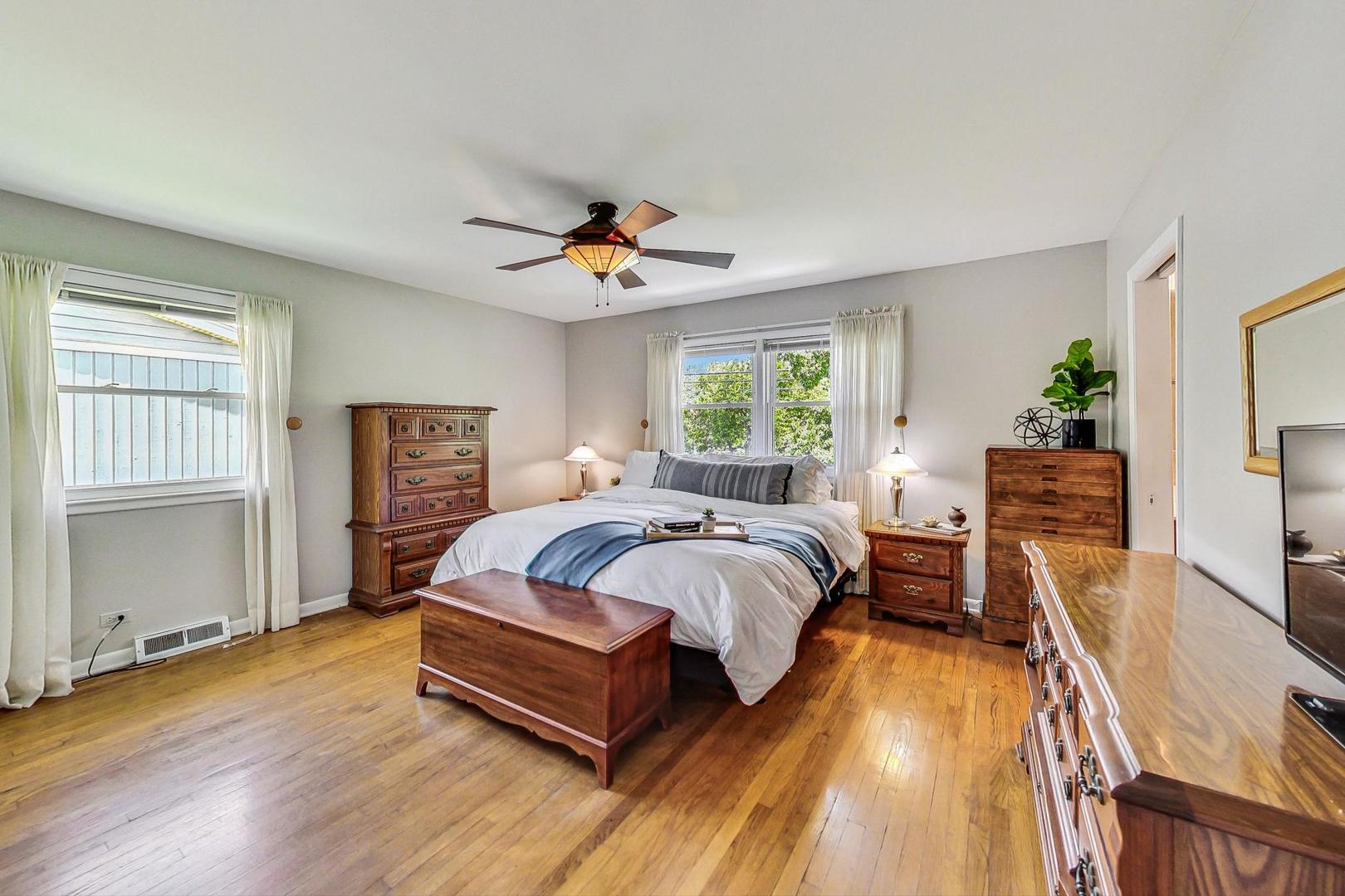 910 Whitegate Drive Mount Prospect, IL 60056 - Photo 21 of 38 a spacious bedroom with a bed a table and a dresser with wooden floor