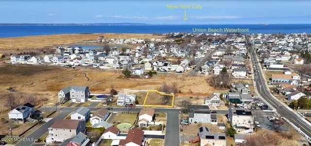an aerial view of ocean and residential houses with outdoor space