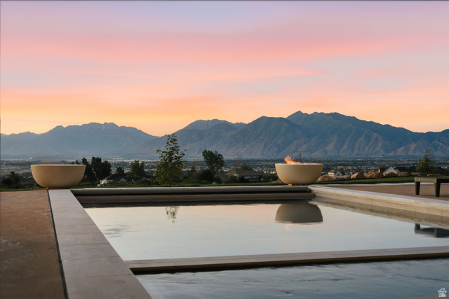 923 North Emery Lane Elk Ridge, UT 84651 - Photo 92 of 101 Outdoor pool with surrounding hardscape, two decorative fire bowls, and a mountain backdrop