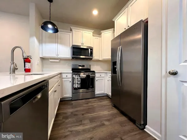 a kitchen with stainless steel appliances kitchen island granite countertop a refrigerator a sink dishwasher a stove and a microwave