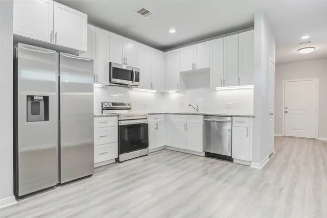 a kitchen with white cabinets stainless steel appliances and a refrigerator