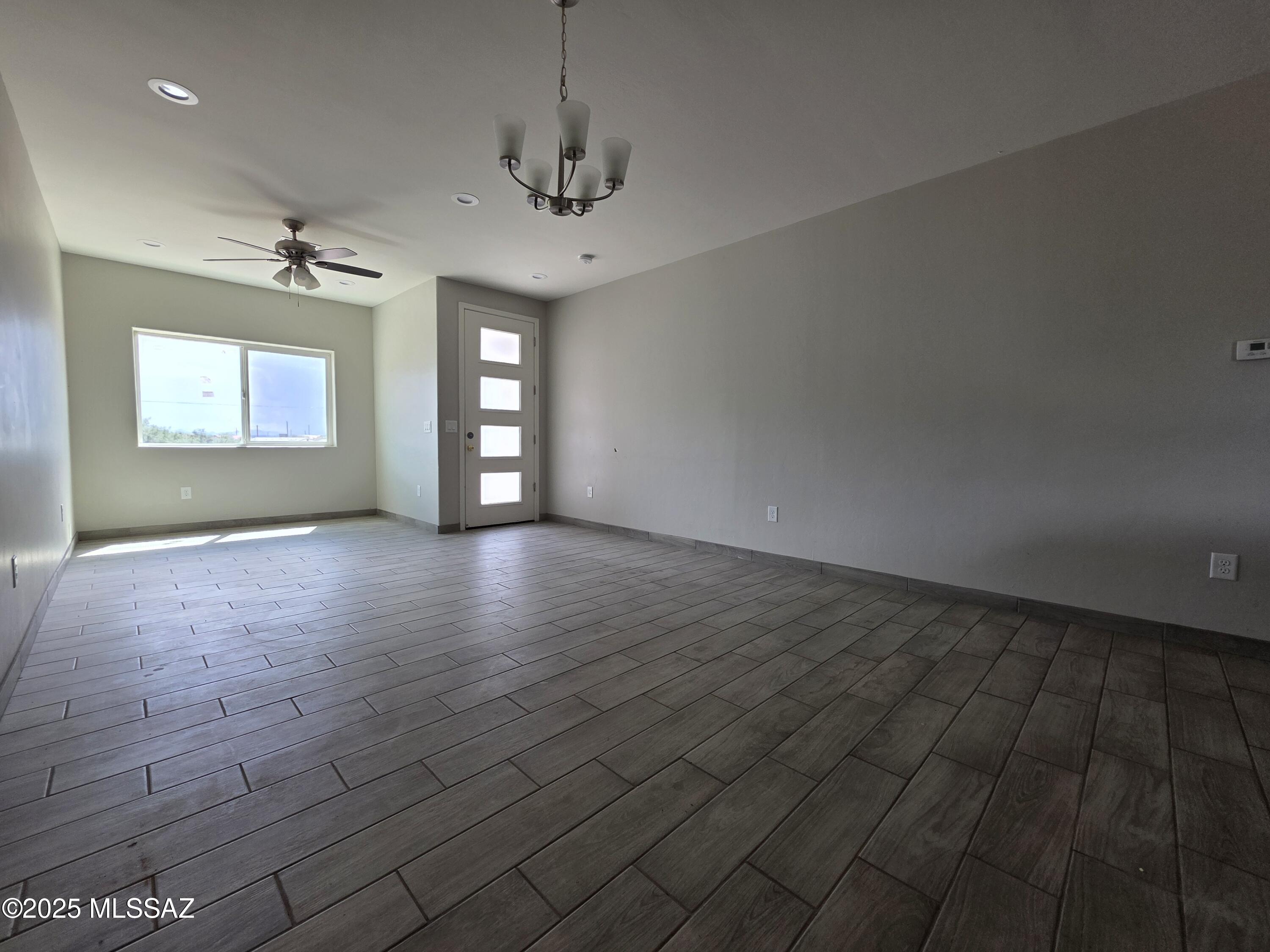 120 Via Venezuela Rio Rico, AZ 85648 - Photo 12 of 37 an empty room with wooden floor chandelier and windows