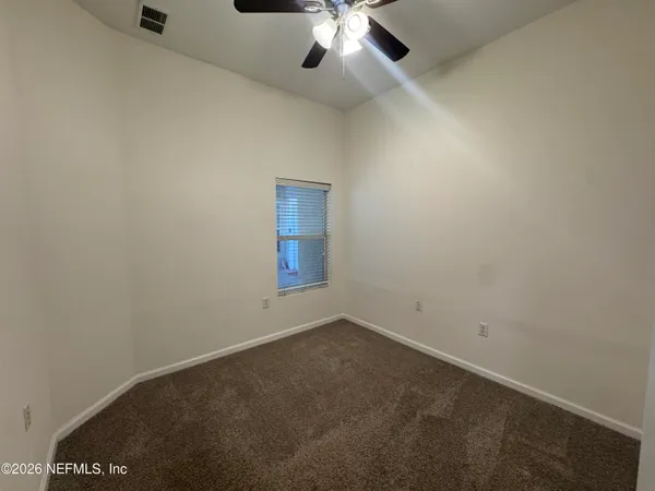 an empty room with a chandelier fan and windows