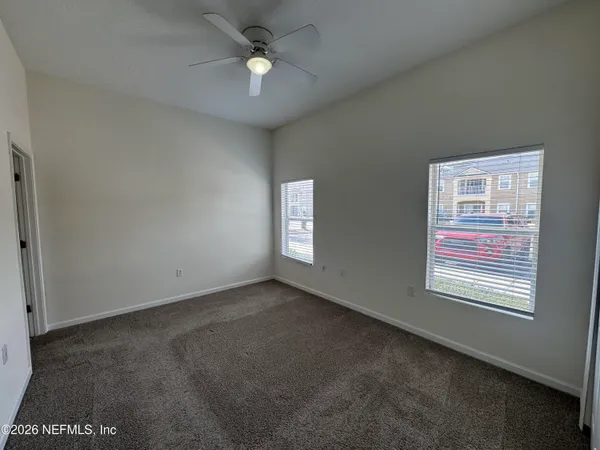 an empty room with windows and fan