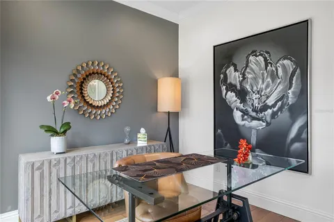 a dining room with wooden floor a chandelier a glass table and chairs