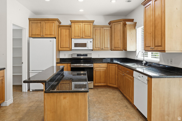 2190 750 West Perry, UT 84302 - Photo 17 of 42 Kitchen featuring wood cabinetry, dark countertops, an island with a breakfast bar, stainless steel appliances, and a pantry with shelving